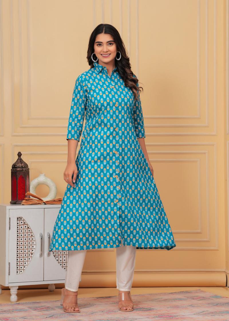 Woman wearing a blue patterned kurta with white pants in a room with yellow walls and a white cabinet.