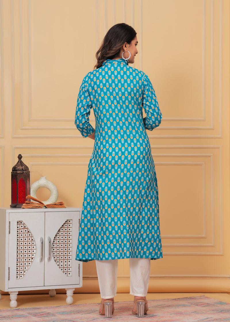 Woman wearing a blue patterned kurta in a room with a white cabinet and decorative items.